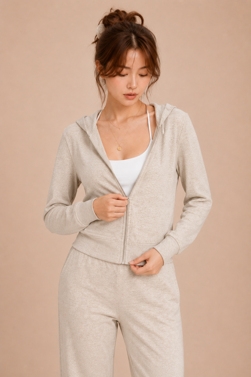 Woman wearing a beige zip-up hoodie and pants on a beige background