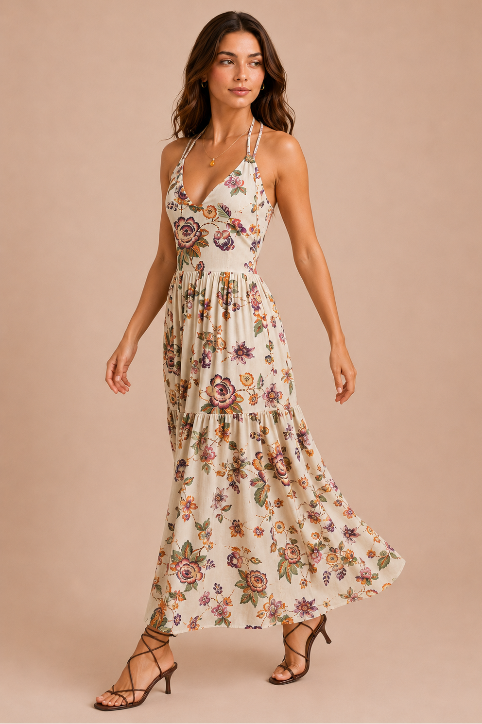 A woman in front of a beige backdrop wearing a white flowy dress featuring a multicolored floral print throughout it. 