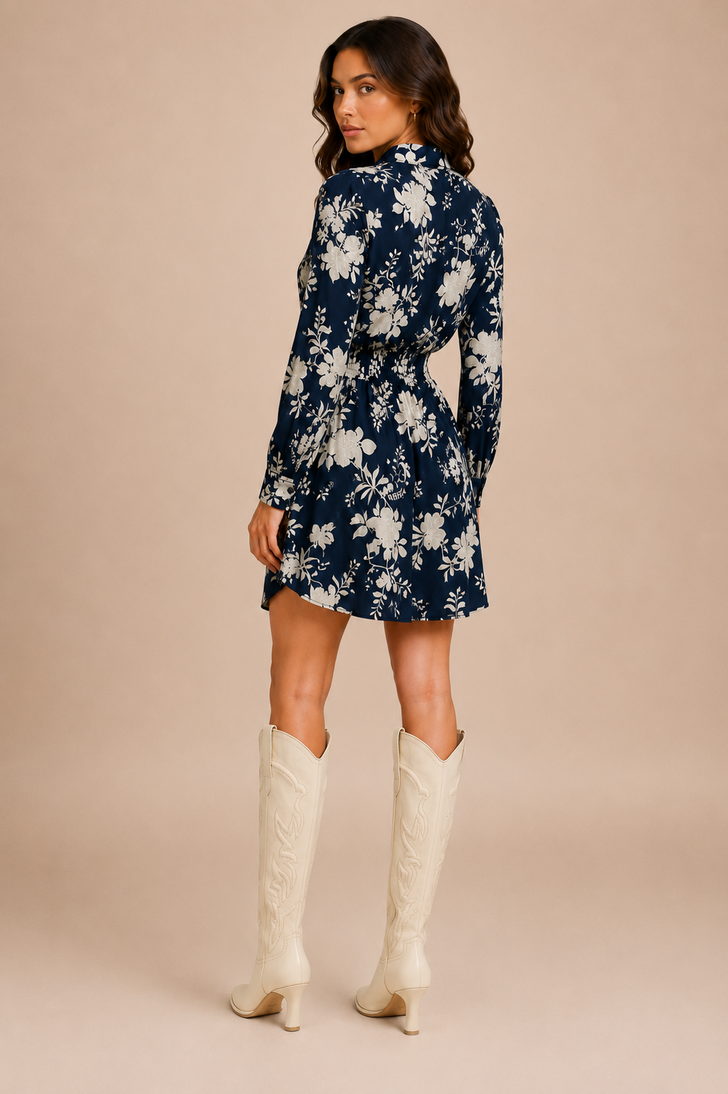 Woman wearing a navy floral dress with white boots on a beige background