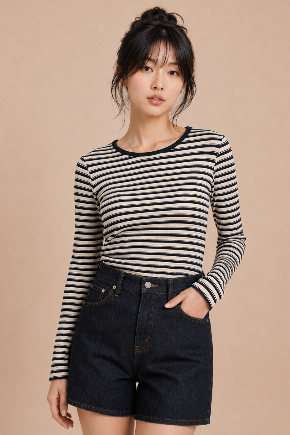 Woman wearing a striped long-sleeve shirt and black shorts against a beige background
