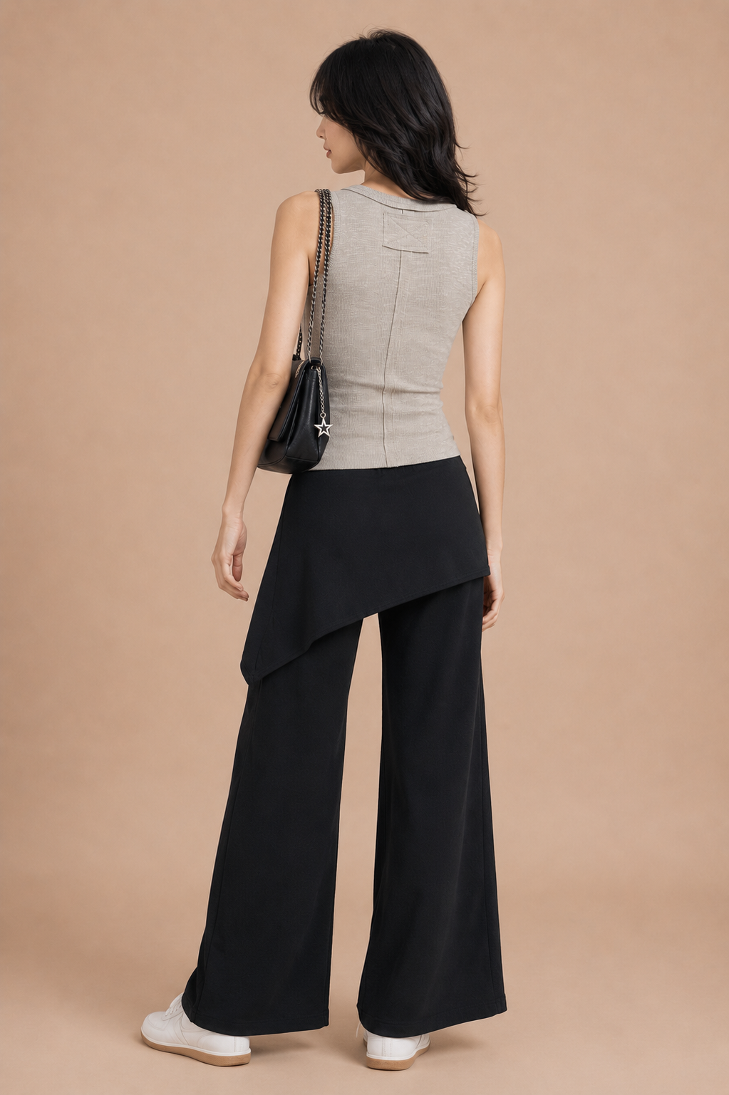 Woman wearing a beige sleeveless top and black wide-leg pants on a beige background