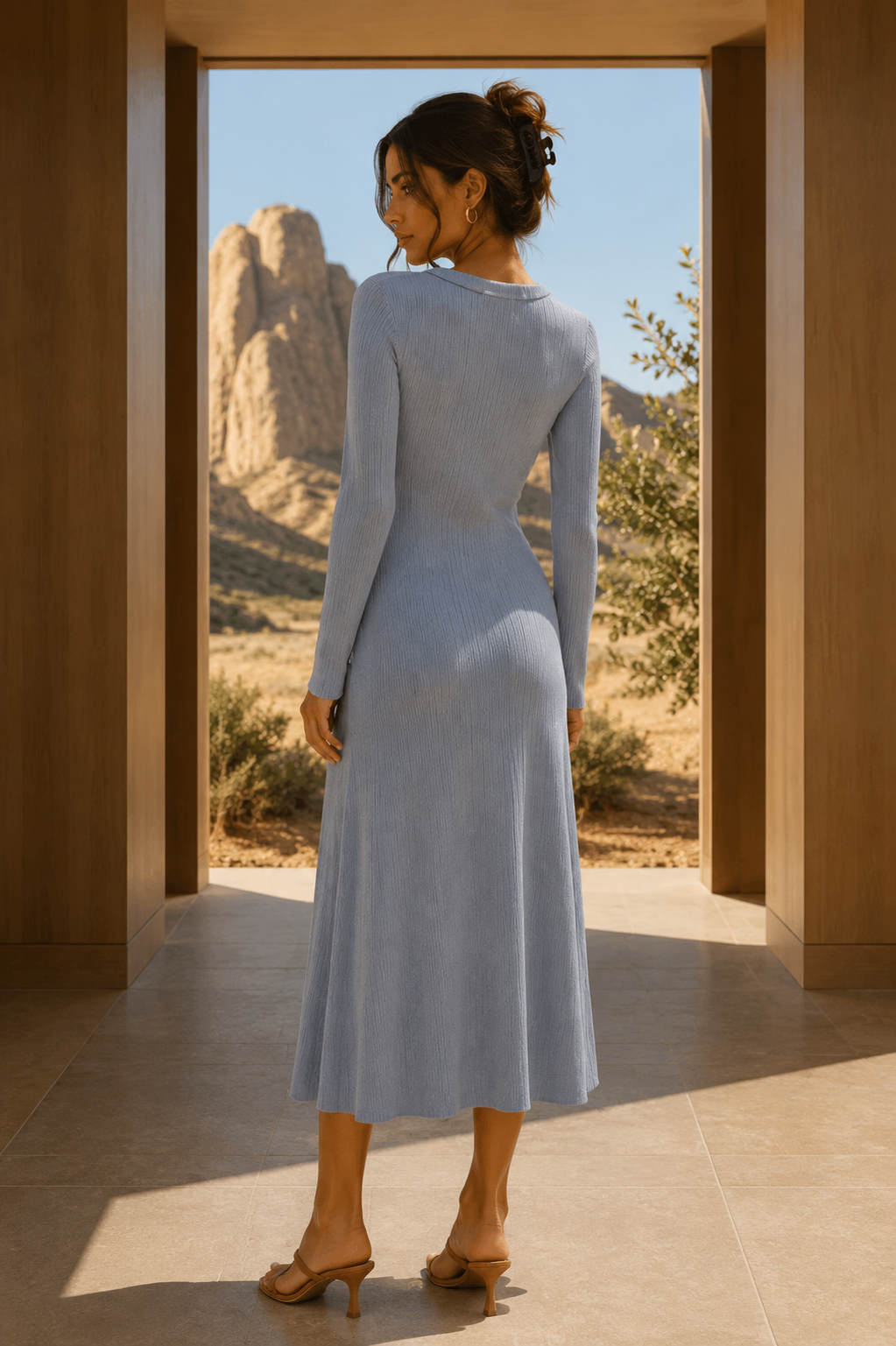 Woman in a light blue dress standing in a doorway with desert scenery outside