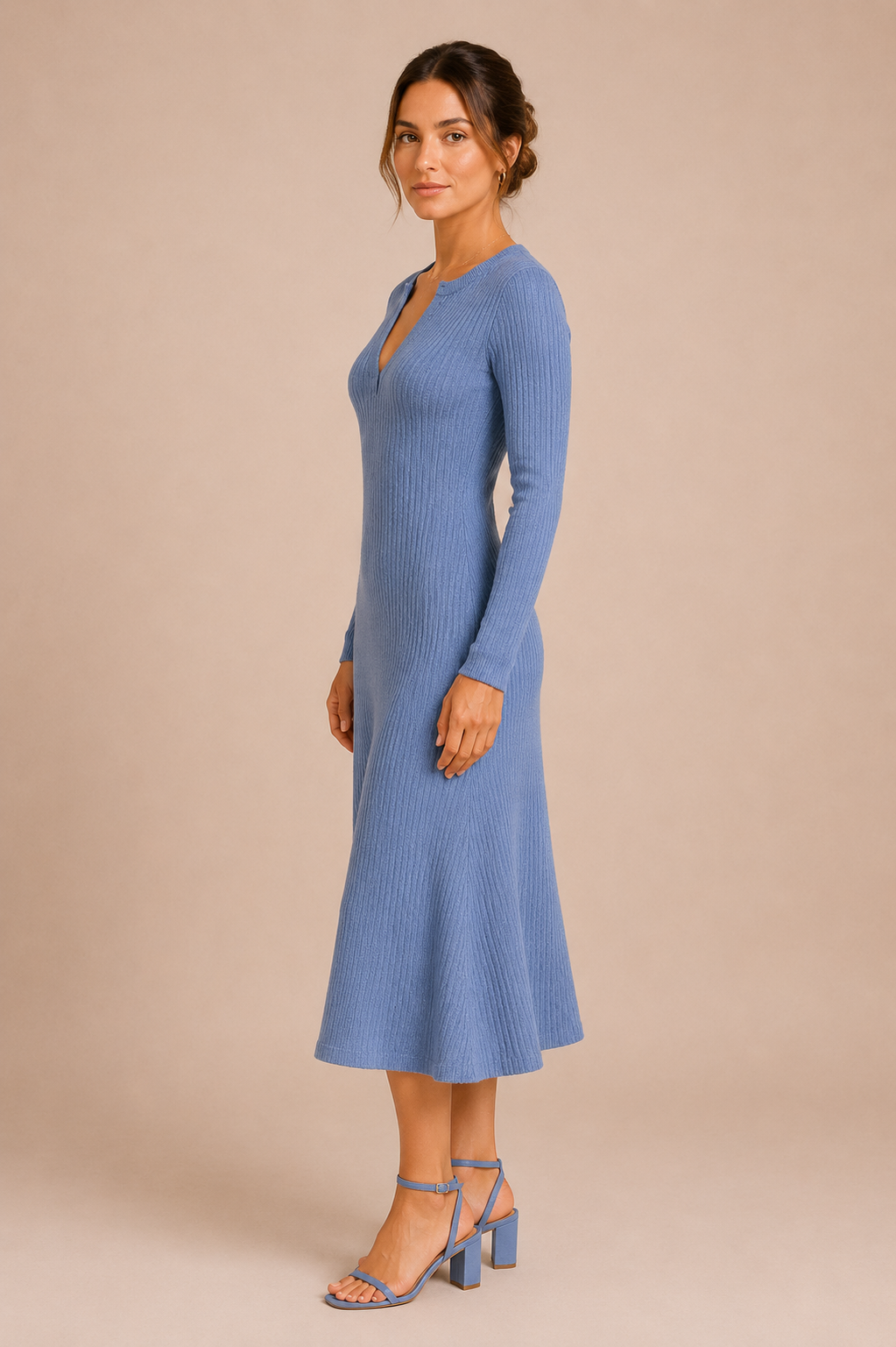 Woman wearing a blue ribbed dress against a beige background