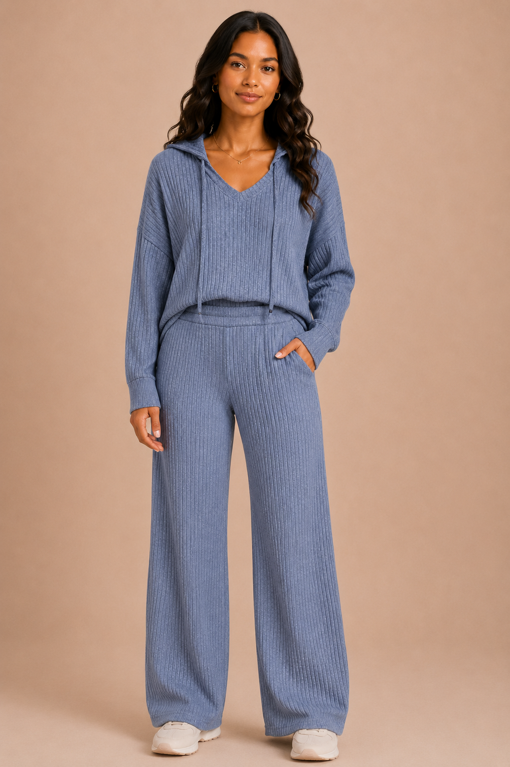 Woman wearing a blue ribbed knit outfit on a beige background