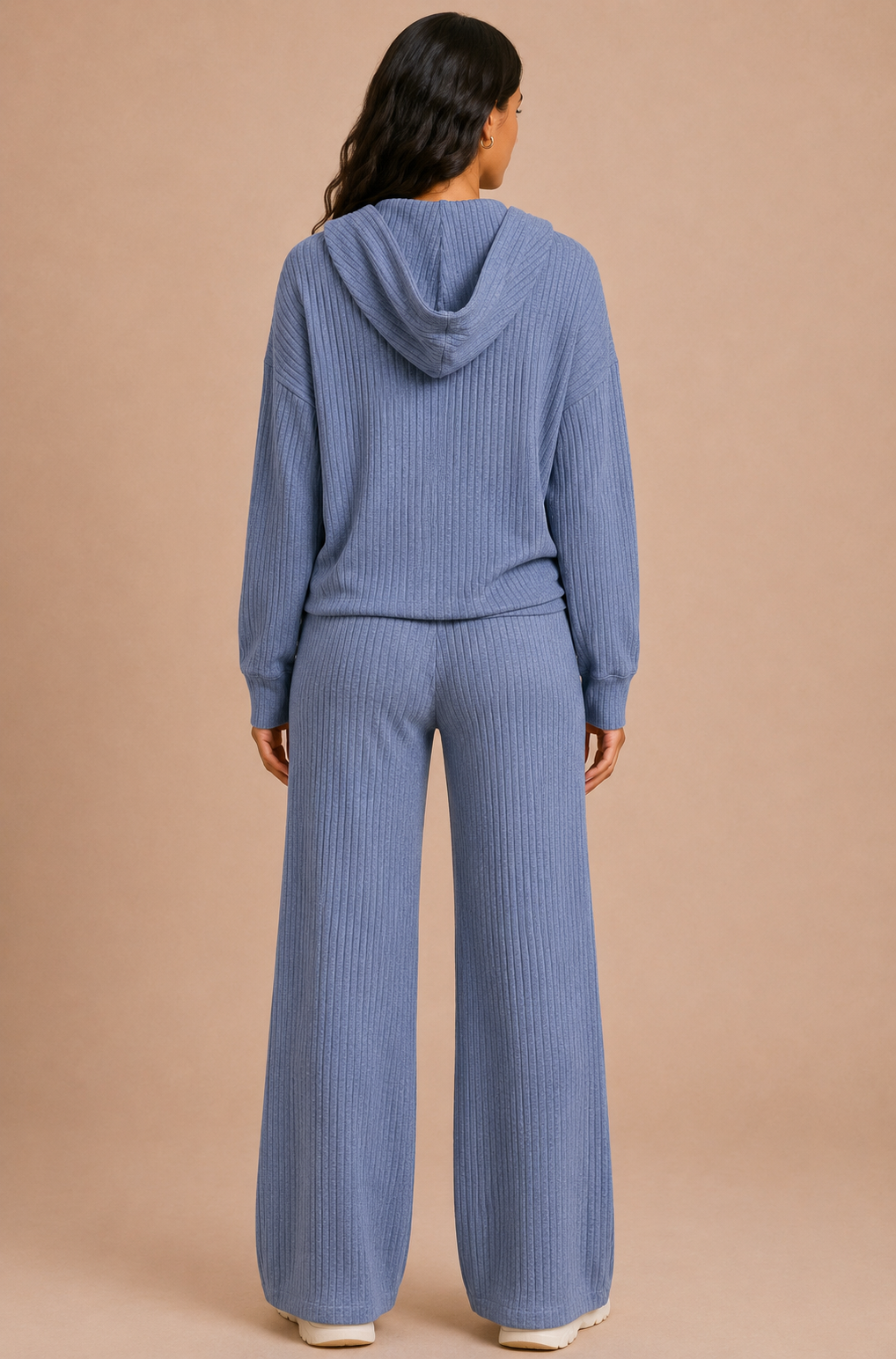 Person wearing a blue ribbed hoodie and pants set on a beige background
