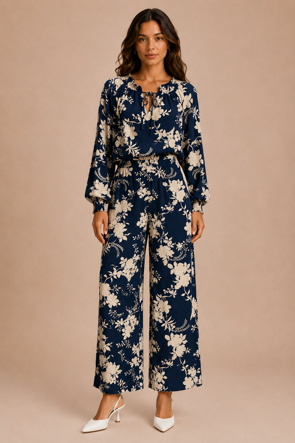 Woman wearing a navy floral blouse and matching pants against a beige background.
